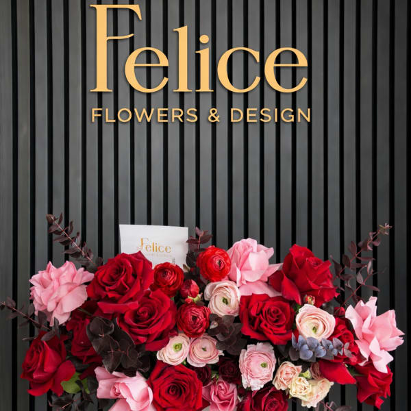 Red and pink rose arrangement in a white vase