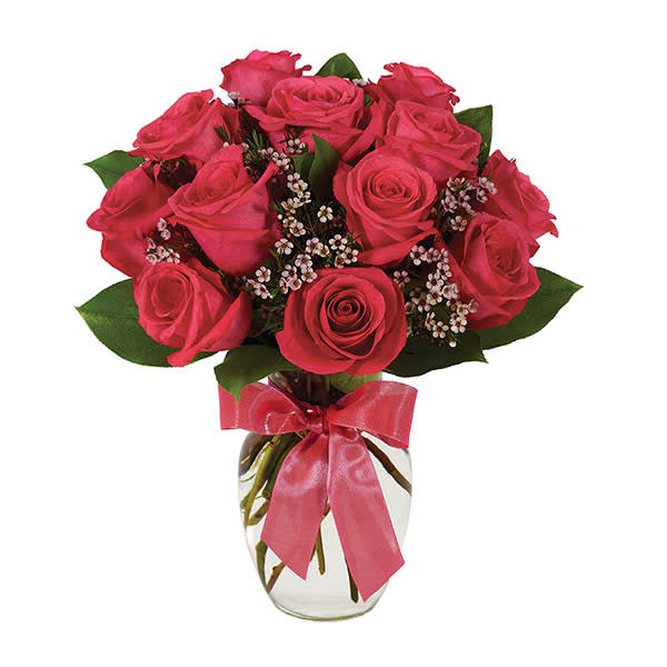 Pink rose bouquet in a clear glass vase with a pink ribbon