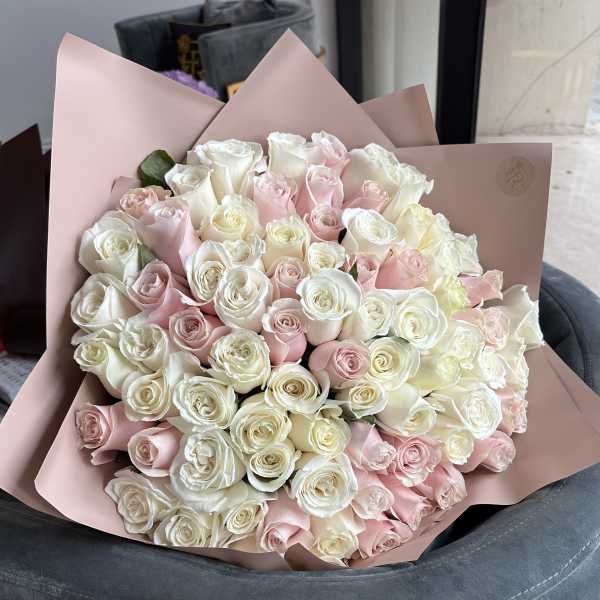 Large bouquet of pale pink and white roses wrapped in blush paper