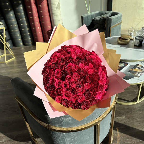 Large round bouquet of red roses wrapped in pink and gold paper