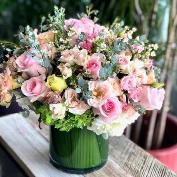 Pink and peach roses arranged in a green glass vase