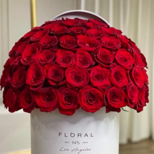 Dome of red roses arranged tightly in a white hat box on a table