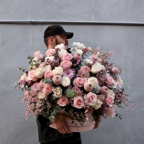 Large pink and white flower arrangement in a round box