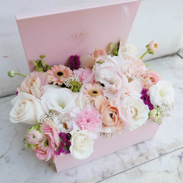 Pastel flower arrangement in a pink gift box with roses and gerbera daisies