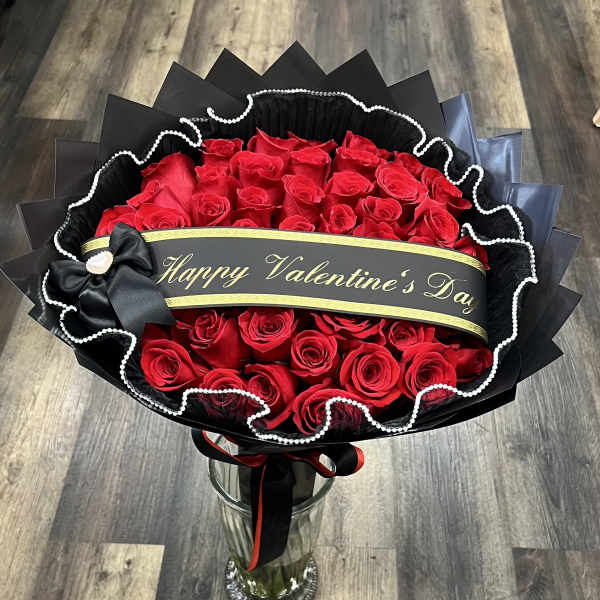 Red rose bouquet wrapped in black paper with a Valentine’s Day ribbon