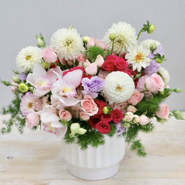 Mixed bouquet of pink, white, and red flowers in a white vase