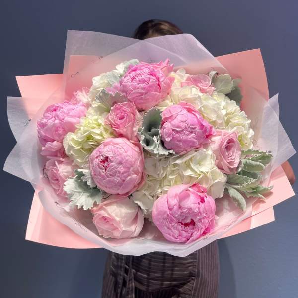 Large bouquet of pink peonies and pale roses wrapped in pink paper