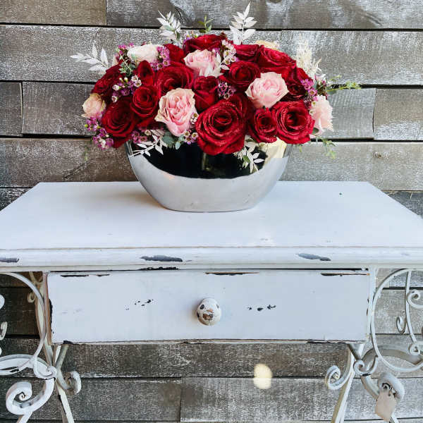Red and pink roses arranged in a silver bowl vase