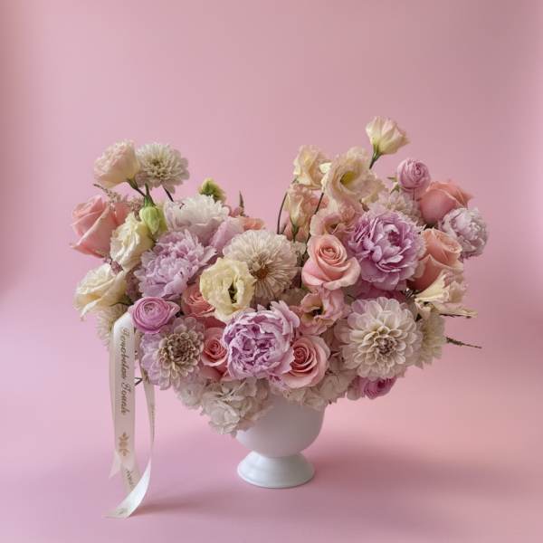 Pink and white flower arrangement in a white pedestal vase