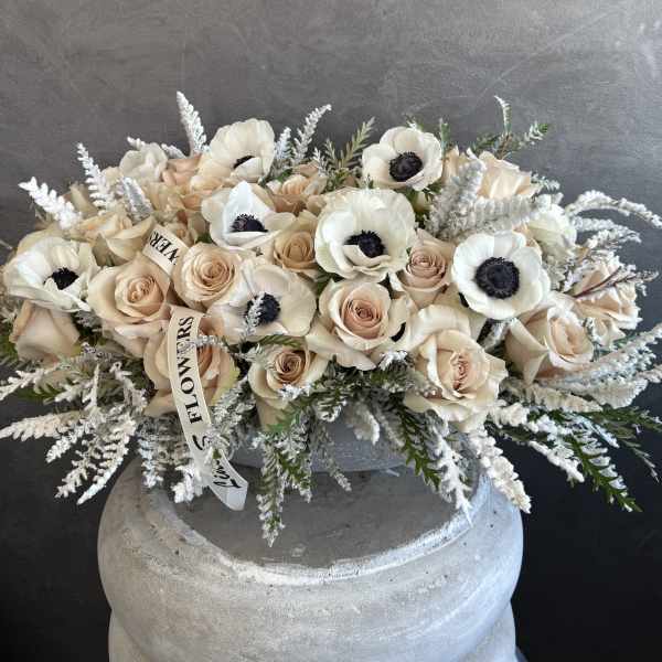 Cream roses and white anemones arranged in a low vase.