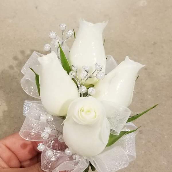 Small white floral corsage with ribbon and pearl accents
