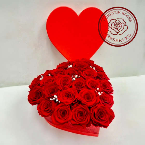 Heart-shaped box filled with red roses and a red heart topper