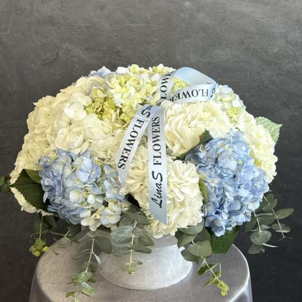 Blue and white hydrangea arrangement in a white hat box with ribbon