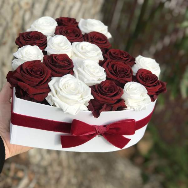 Heart-shaped box of red and white roses with a red ribbon bow