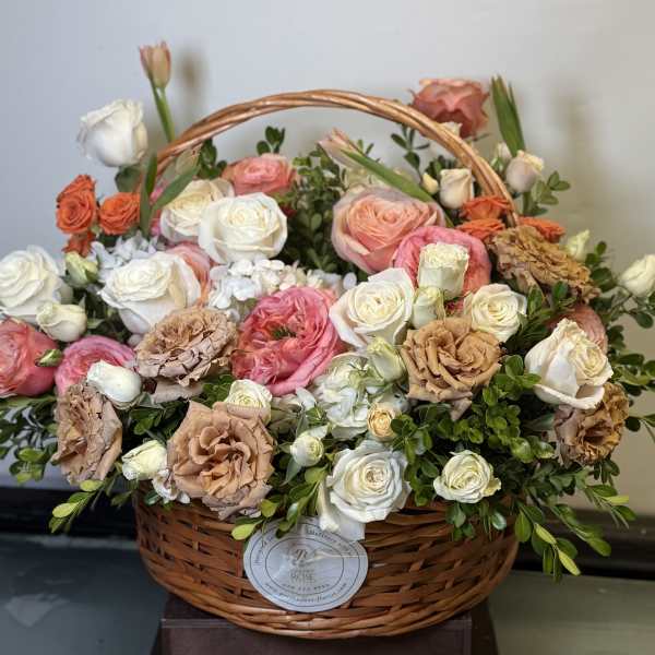 Basket of pink, white, and peach roses with greenery