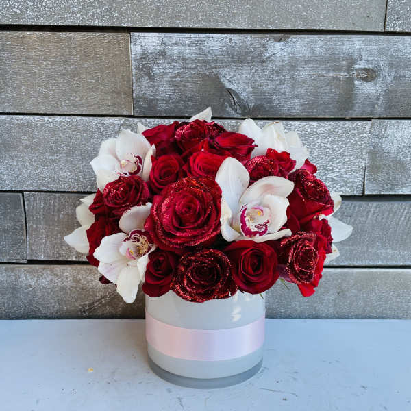 Red roses and white orchids in a round white box