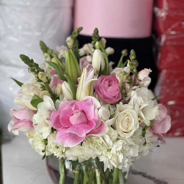 Pink and white flowers arranged in a clear glass vase