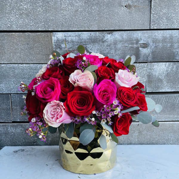 Bouquet of red, pink, and white roses in a gold vase