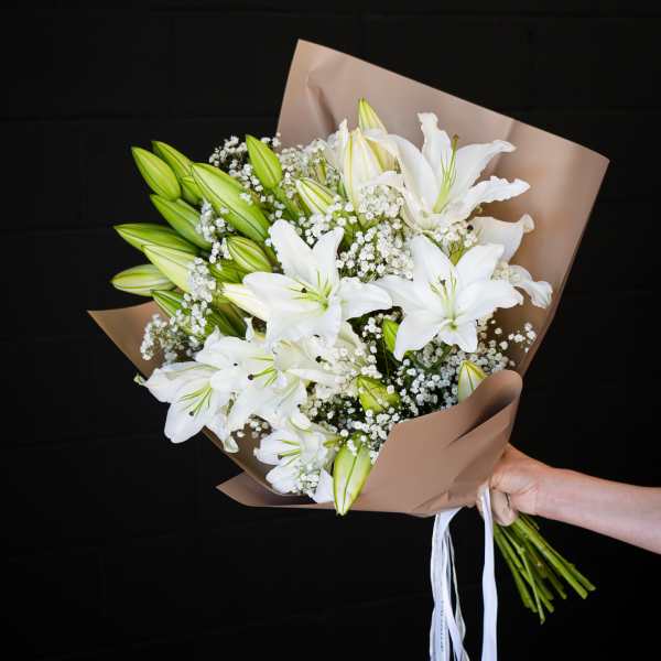 Bouquet of white lilies and baby's breath wrapped in brown paper