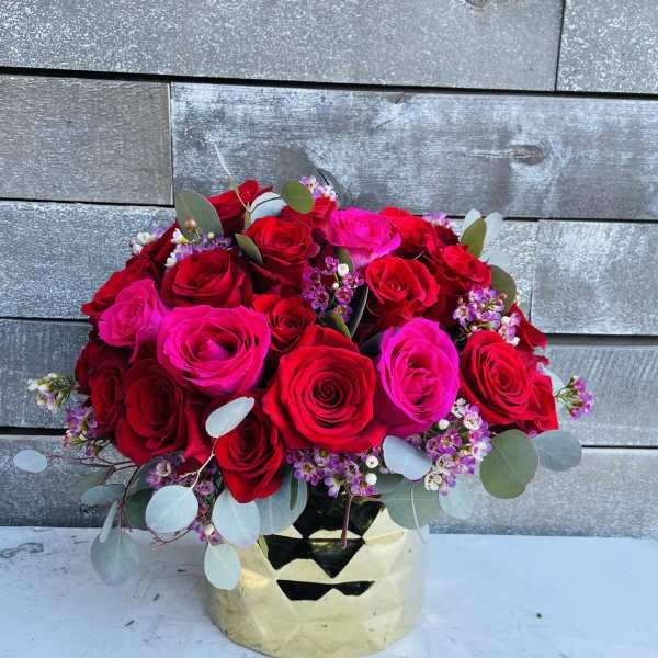 Bouquet of red and hot pink roses in a gold vase