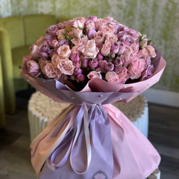 Large bouquet of pink and lavender roses wrapped in pastel paper