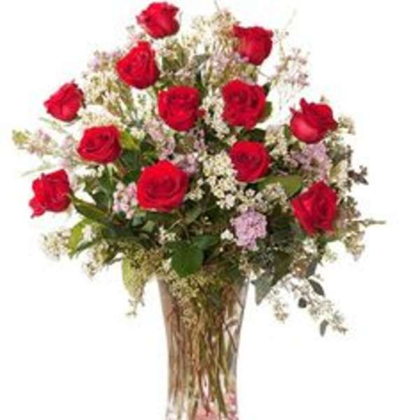 Red roses in a clear glass vase with small filler flowers