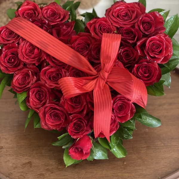 Heart-shaped bouquet of red roses tied with a red ribbon