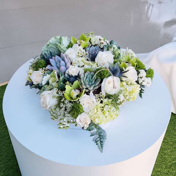 Low floral arrangement with white roses and succulents on a round table