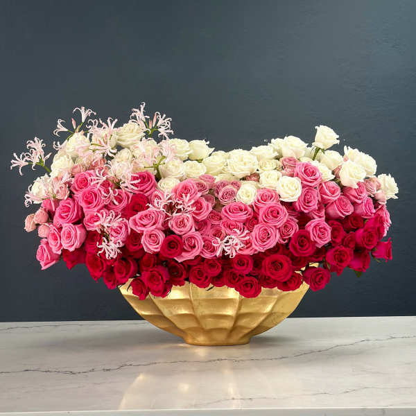 Large arrangement of pink, red, and white roses in a gold vase