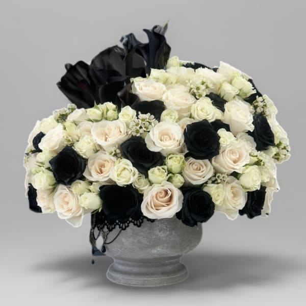 Black and white rose arrangement in a gray urn vase