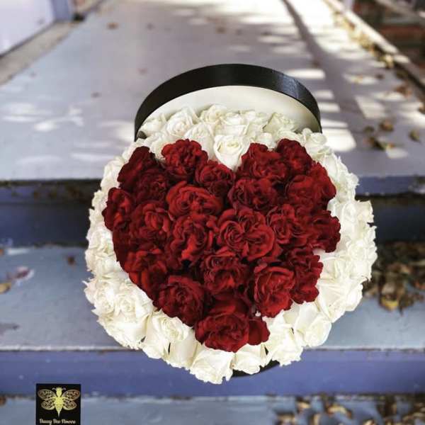 Round box of white roses with red roses arranged in a heart shape on top