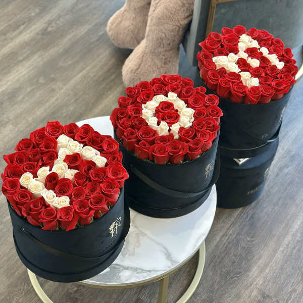 Three round boxes of red and white roses arranged on tables