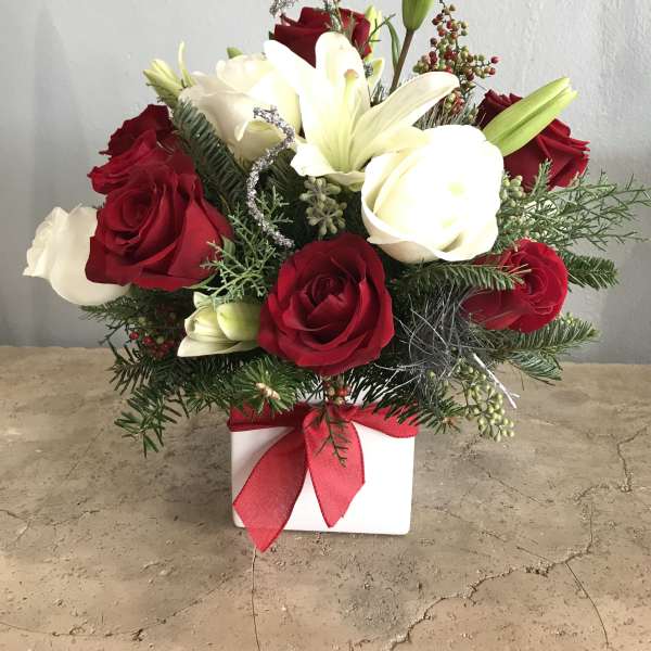 Red and white rose arrangement with lilies in a white box tied with a red ribbon