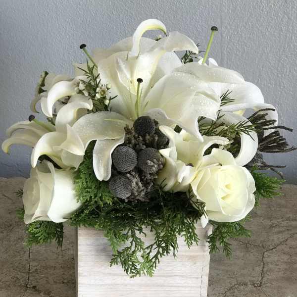 White calla lilies and roses arranged in a white wooden box