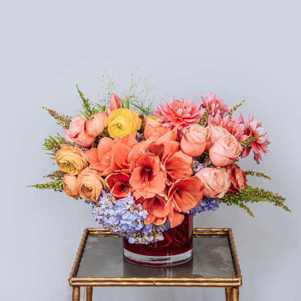 Coral and pink floral arrangement in a red glass vase