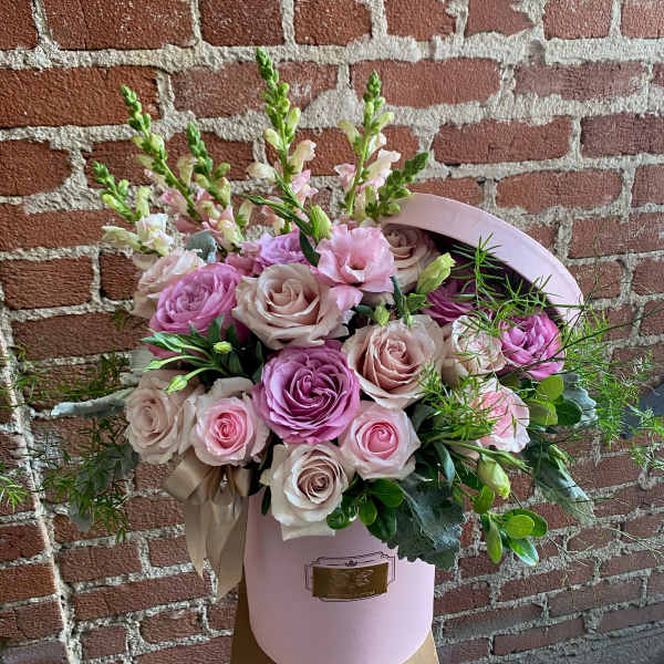 Pink and blush roses arranged in a pink hat box