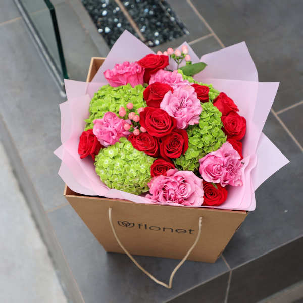 Pink and red rose bouquet with green hydrangeas in a cardboard gift box