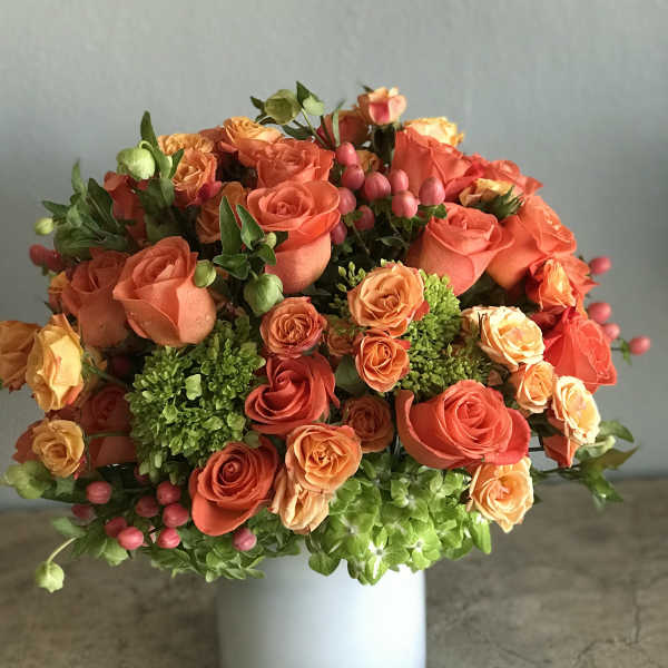 Orange and peach rose bouquet in a white vase