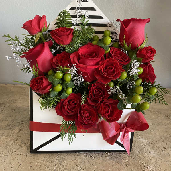 Red roses arranged in a black-and-white gift box with a red ribbon