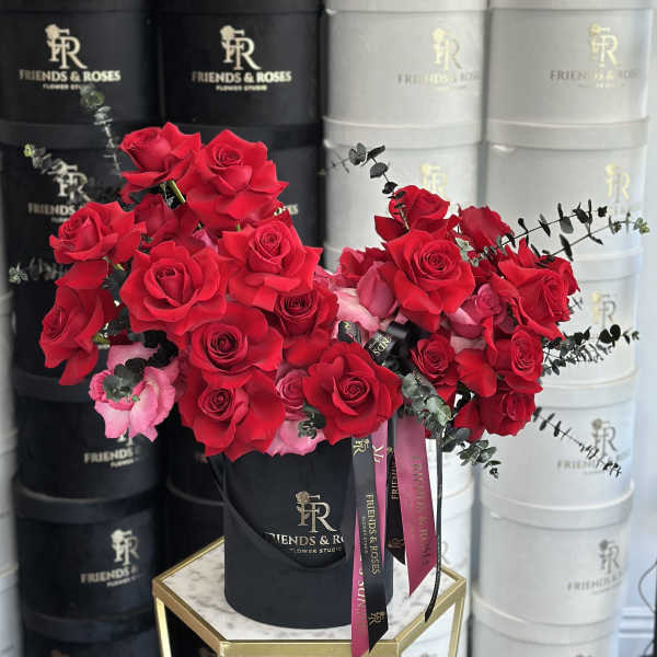 Two bouquets of red roses in black boxes with pink roses and eucalyptus.