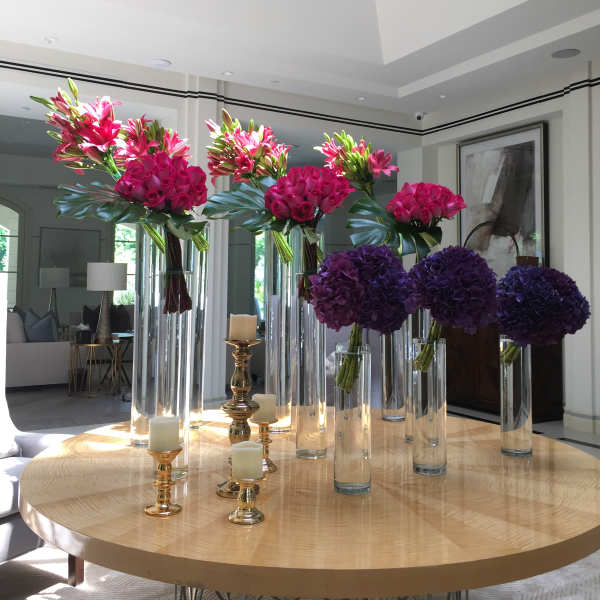 Tall floral centerpieces with pink lilies, roses, and purple hydrangeas in glass vases