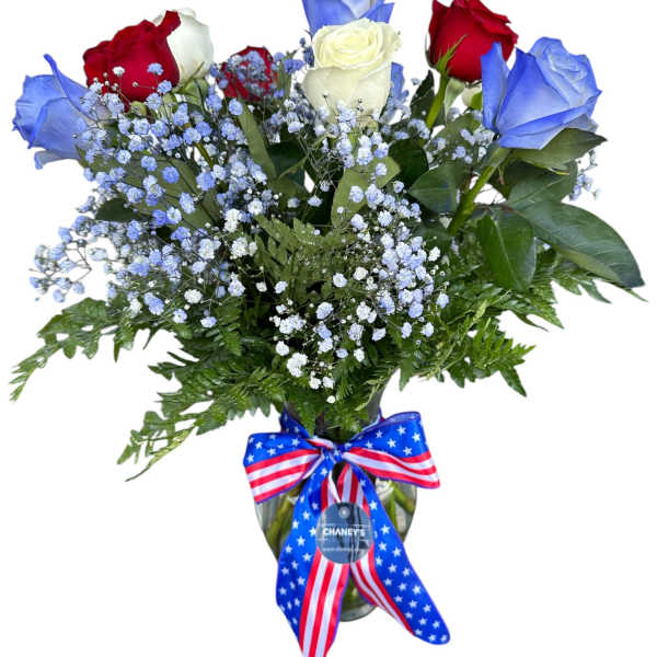 Bouquet of red, white, and blue roses in a glass vase with a patriotic ribbon