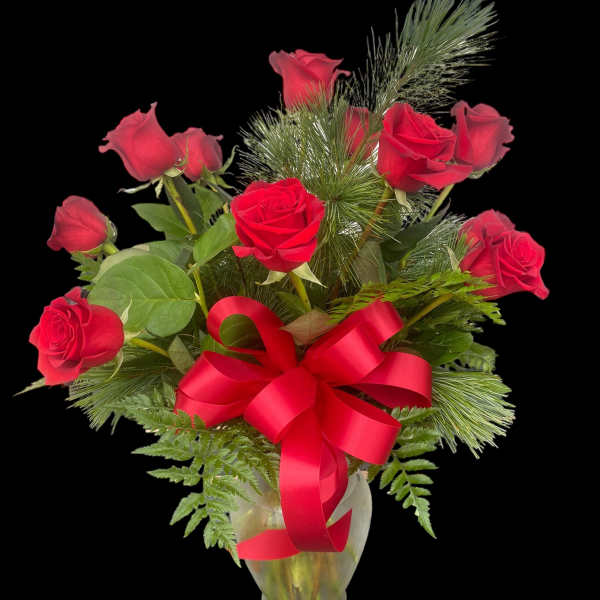 Red roses arranged in a clear glass vase with a red ribbon bow