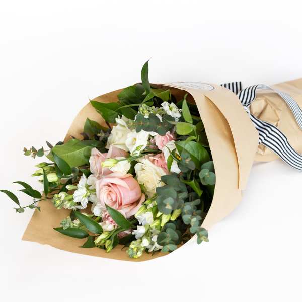 Bouquet of pink and white roses wrapped in kraft paper