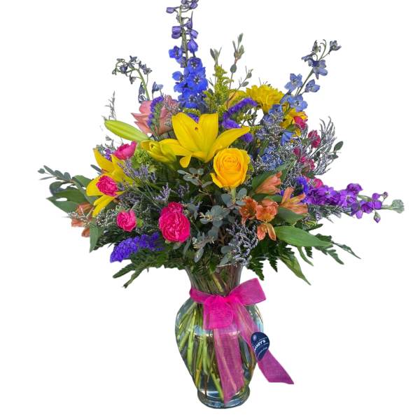 Colorful mixed bouquet in a glass vase with a pink ribbon