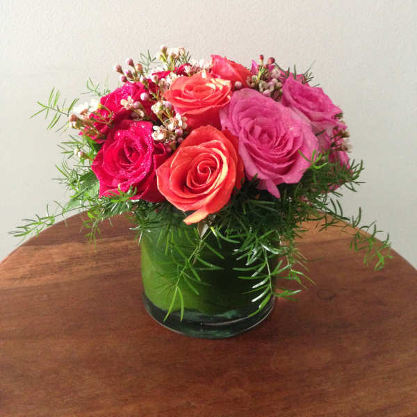 Pink and coral roses arranged in a green glass vase