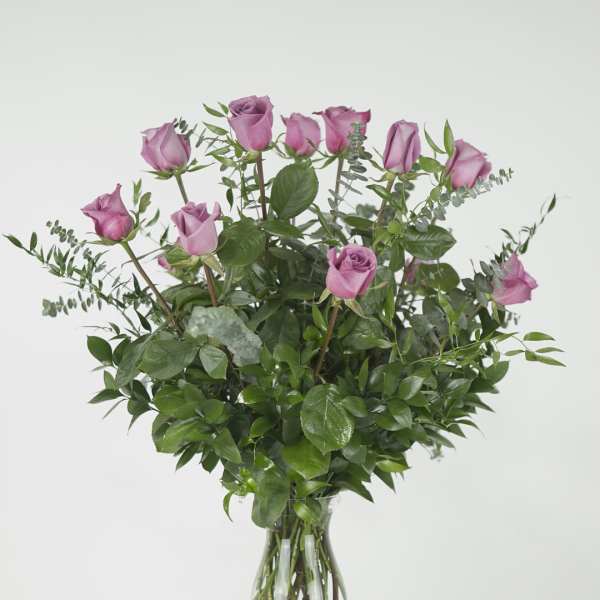 Pink roses in a clear glass vase with mixed greenery