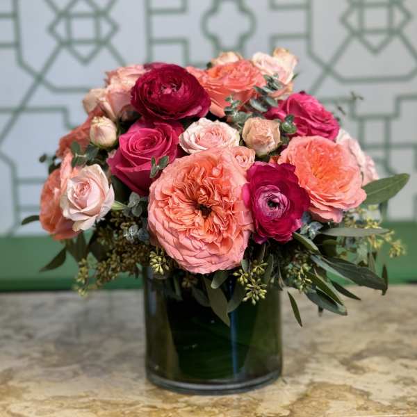 Pink and coral roses arranged in a dark glass vase