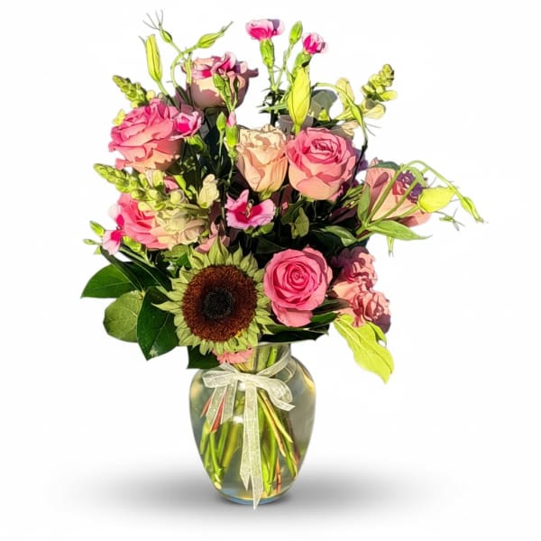 Pink roses and a sunflower arranged in a glass vase with a ribbon.