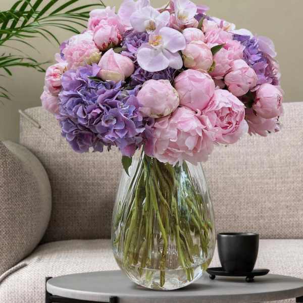 Pink and lavender bouquet in a clear glass vase on a table